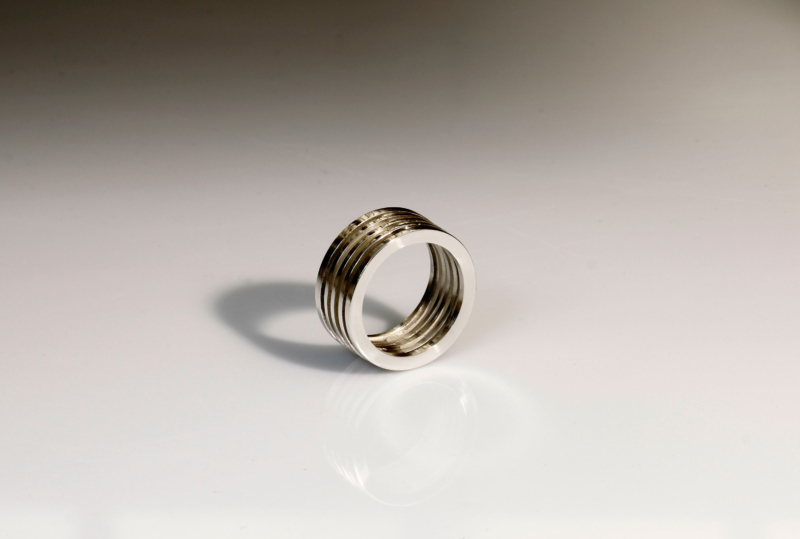 anillo de plata formado por aros paralelos en fondo gris degradado